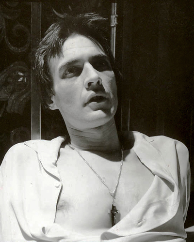 Tim Kent as the priest, looking distressed and wearing a cross necklace