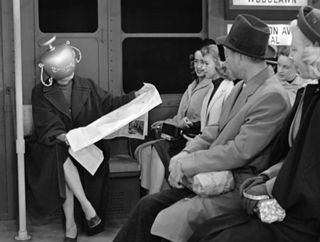 I Love Lucy subway image - woman wearing a vase on her head on a train with passengers staring at her