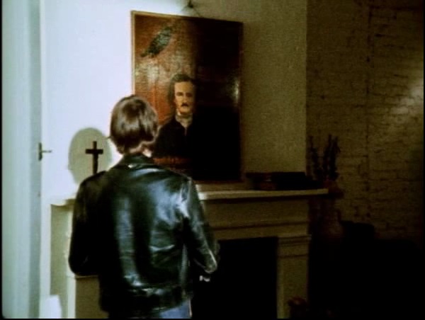 Man standing before a portrait of Poe and a cross